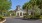 a large driveway next do a clubhouse with several trees surrounding it